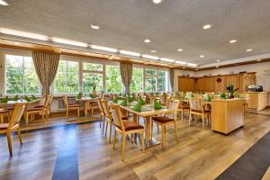 a dining room with tables and chairs and windows at AURA-HOTEL Saulgrub in Oberammergau