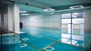 a swimming pool with blue water in a building at Verano Centrum Zdrowia i Relaksu in Kołobrzeg