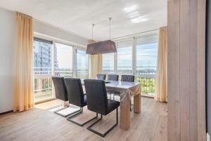 a dining room with a table and chairs and large windows at Hello Zeeland - Appartement Port Scaldis 15-042 in Breskens