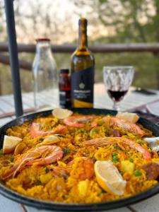 a plate of food with shrimp and rice and a bottle of wine at Casa KiSi Cottage, Rural Boutique Bed & Breakfast in Málaga