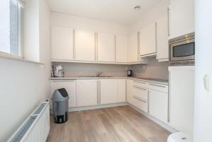 a white kitchen with white cabinets and a sink at Hello Zeeland - Appartement Port Scaldis 11-112 in Breskens +8 photos