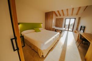 a bedroom with a bed with a green headboard and a table at Finca Son Oms in Porreres