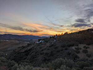 a view of a hill with trees and a sunset at Casa KiSi Cottage, Rural Boutique Bed & Breakfast in Málaga