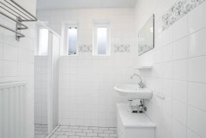 a white bathroom with a sink and a toilet at Hello Zeeland - Vakantiehuis Schelde 194 in Breskens +5 photos