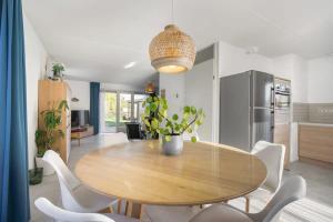 a dining room with a wooden table and white chairs at Hello Zeeland - Vakantiehuis Zwin 004 in Breskens