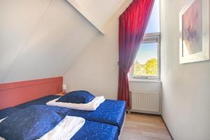 a bedroom with a bed with blue sheets and a window at Hello Zeeland - Vakantiehuis Zwin 004 in Breskens