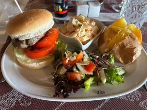 a plate with a hamburger and a salad and chips at Casa KiSi Cottage, Rural Boutique Bed & Breakfast in Málaga