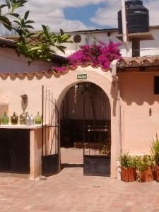 una entrada a un edificio con una puerta con flores púrpuras en Hostería El Zaguan en Cafayate