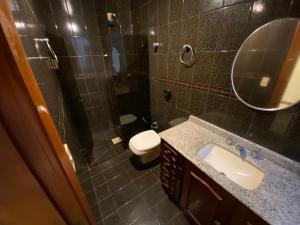 un bagno con lavandino, WC e specchio di Apartamento quadra mar a Meia Praia