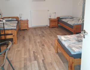a room with three beds and wooden floors at FeWo PAN in Pfarrkirchen