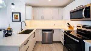 Una cocina blanca con fregadero y lavavajillas. en Sapphire Beach 213 apts, en Christ Church