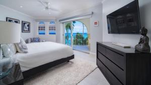 Un dormitorio con una cama grande y un televisor. en Sapphire Beach 213 apts, en Christ Church 12 fotos más