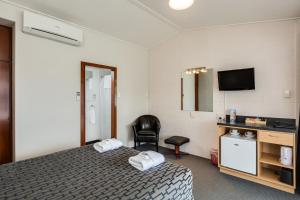 a hotel room with a bed and a chair at Ocean Beach Hotel in Dunedin