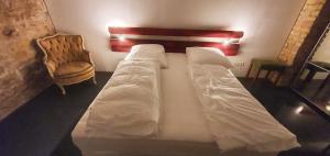 a large white bed in a room with a chair at 1-Zimmer-Wohnung im Loft in Mannheim