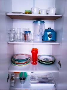 a shelf filled with plates and cups and dishes at Apartamento Praia Coqueiral de Itaparica - Vila Velha in Vila Velha