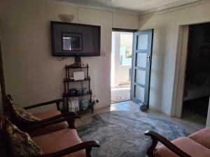 a living room with two chairs and a tv on the wall at Karoo-rus in Montagu
