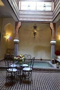 une chambre avec une table et des chaises à côté d'une piscine dans l'établissement Riad Charik, à Marrakech