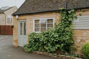 a brick house with a window and a bush at The Redesdale in Moreton in Marsh
