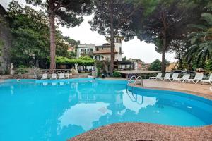 a swimming pool with chairs and a house in the background at Appartamento Bilocale Moneglia 21 in Moneglia
