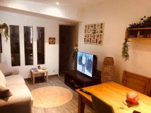 a living room with a couch and a tv and a table at Chez Bel Isa in Tallard