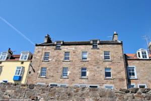 Un viejo edificio de ladrillo sobre un muro de piedra. en Harbour Haven- idyllic coastal retreat, en Anstruther