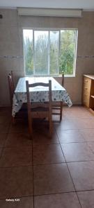a table and chair in a room with a window at Cabanas y hostal tepual puerto montt in Puerto Montt