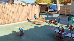 Un niño sentado en un patio de recreo con algunos columpios. en Camping La Bergerie Plage, en Hyères