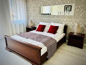 a bedroom with a large bed with red pillows at Kwartał Dominikański in Kamień Pomorski