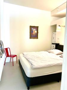 a bedroom with a bed and a red chair at Apartment close to campus in Nijmegen