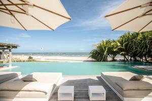 a pool with white chairs and an umbrella and the beach at Preabeach Boutique Hotel & SPA in Prea