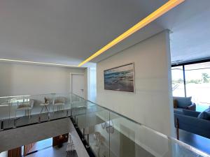 a glass staircase in a house with a blue couch at Grand Lux House Barra São Miguel Hosti Hospedagens in Barra de São Miguel +148 photos