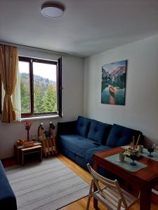 a living room with a blue couch and a table at Kopaonik apartman 11 in Kopaonik