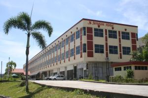 a building with a palm tree in front of it at Jeruton Hotel in Kampong Jerudong