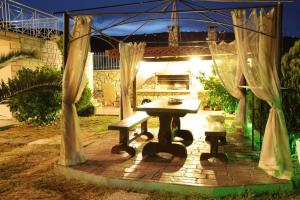 una mesa de picnic y un banco en un patio trasero por la noche en Villa Christine - Maisonettes with fireplace, en Aliveri