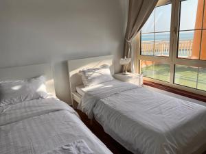 two beds in a room with a window at رويال مارينا بانوراما ثلاث غرف Royal Beach family and businesses in King Abdullah Economic City +98 photos