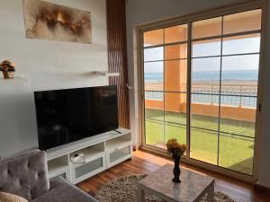 a living room with a large television and a large window at رويال مارينا بانوراما ثلاث غرف Royal Beach family and businesses in King Abdullah Economic City