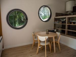Un comedor con mesa y sillas y dos ventanas redondas. en Maison sous le noyer, en Montessut