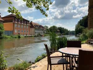 Ein Tisch und Stühle stehen neben einem Fluss in der Unterkunft Concordia33 - Traumferienwohnung an der Regnitz in Bamberg