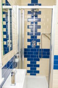 a blue tiled bathroom with a shower and a sink at The Captain Cook in London
