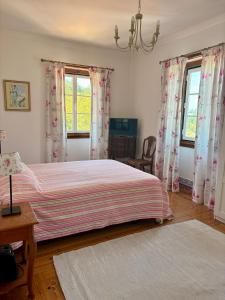 a bedroom with a bed and two windows with curtains at Casa da Villa 1A in Sintra