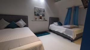 a bedroom with two beds and blue curtains at Casa Hotel Solare de la 70 in Medellín