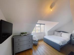 una camera da letto con un letto, una cassettiera e una TV di Amber House a Gorleston-on-Sea