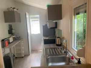 a kitchen with a stainless steel sink and a window at Mobilhome tout confort camping 4 étoiles in La Teste-de-Buch