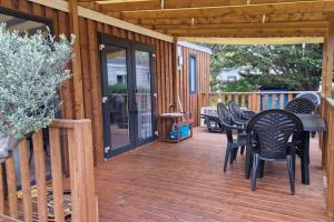 a deck with black chairs and a table on a house at Mobilhome tout confort camping 4 étoiles in La Teste-de-Buch