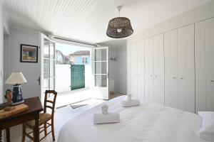 een witte slaapkamer met een bed, een bureau en een raam bij Cocon Douillet, plages à 2 pas in La Noue