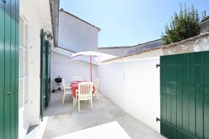 een tafel en stoelen met een parasol op een terras bij Cocon Douillet, plages à 2 pas in La Noue