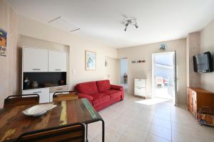 een woonkamer met een rode bank en een tafel bij Cocon Douillet, plages à 2 pas in La Noue