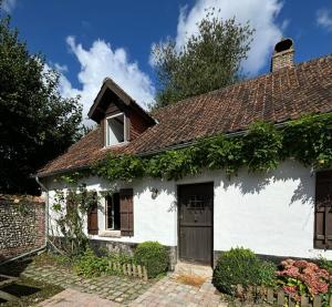a small white house with ivy growing on it at Les Côtières in Maresville