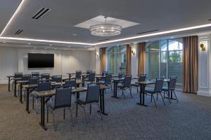 a conference room with tables and chairs and a screen at The Publisher, Downtown Fredericksburg, a Tribute Portfolio Hotel in Fredericksburg