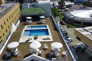 a balcony with a swimming pool and chairs and umbrellas at Royal Flat Service 115 - Tambaú (João Pessoa) 115 in Tambaú
